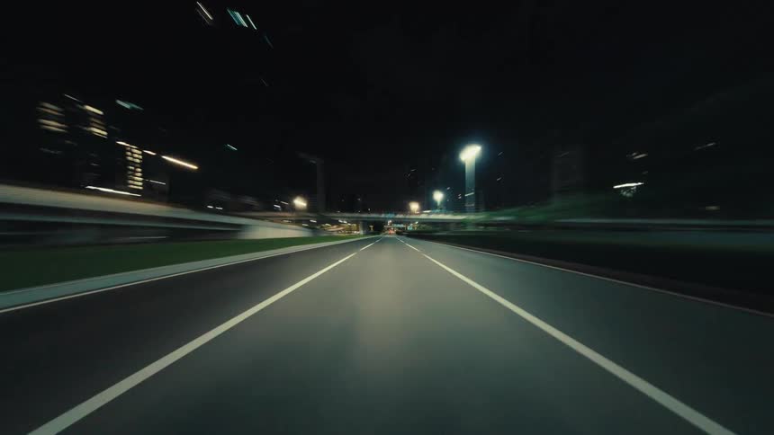 A thrilling point-of-view hyperlapse shows a high-speed drive through a modern city at night, with blurred lights creating dynamic streaks