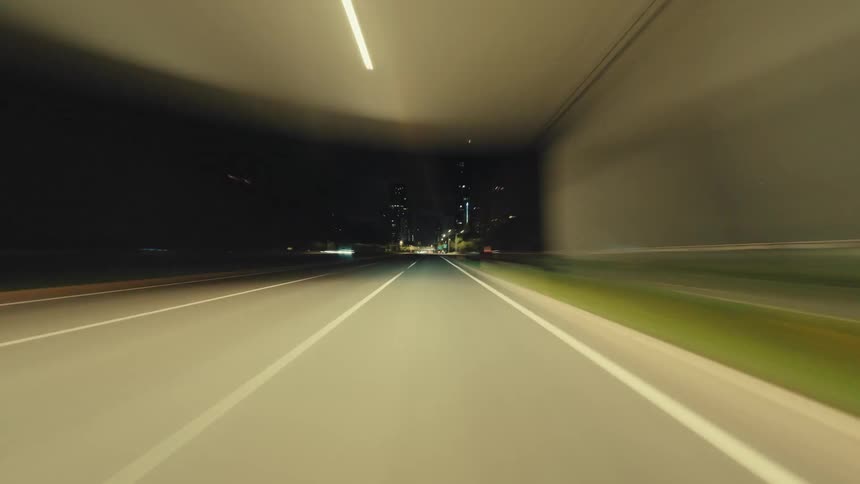 A high-speed hyper-lapse POV drive through a modern city at night, with illuminated streets and buildings streaking by