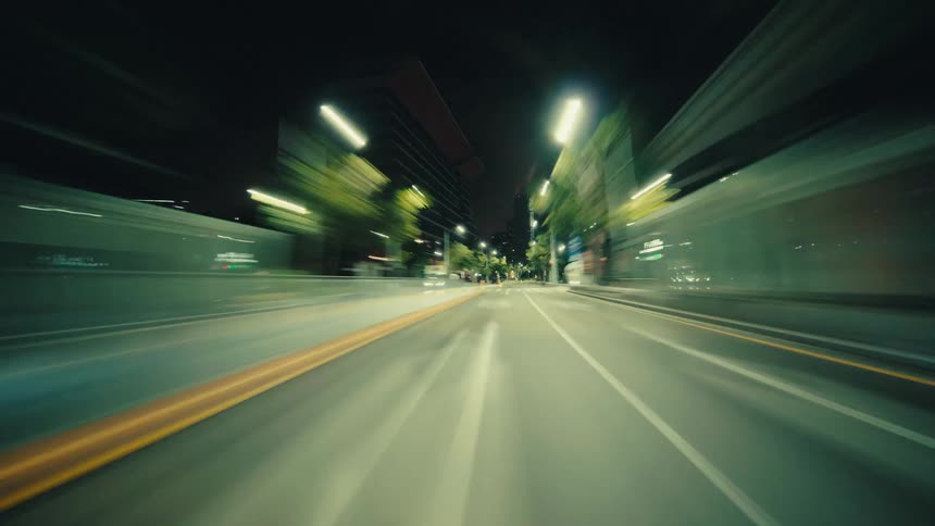 A high-speed hyperlapse captures a thrilling point-of-view drive through a modern city at night as lights blur into streaks