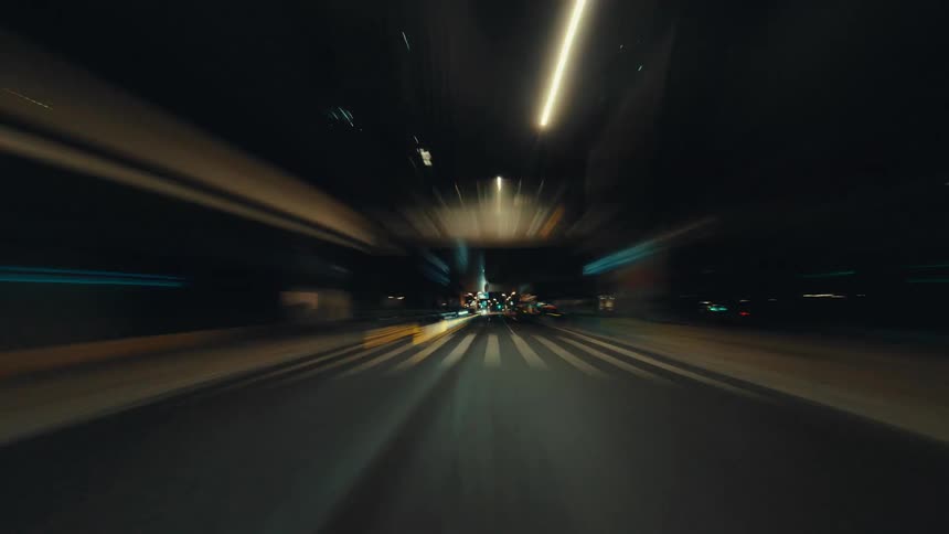 A fast-paced first-person hyperlapse captures the vibrant and blurry light trails while driving through a city at night