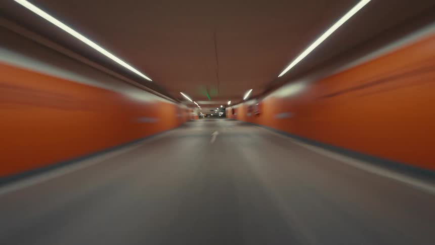 A fast-paced hyperlapse from a driver's point of view speeding through a dimly lit underground parking garage