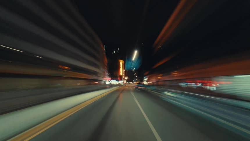 Dynamic first-person hyper-lapse of a fast drive through illuminated city streets and tunnels at night