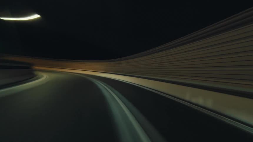An exhilarating POV hyperlapse speeds down a dark highway at night, transforming streetlights and taillights into vibrant streaks of motion