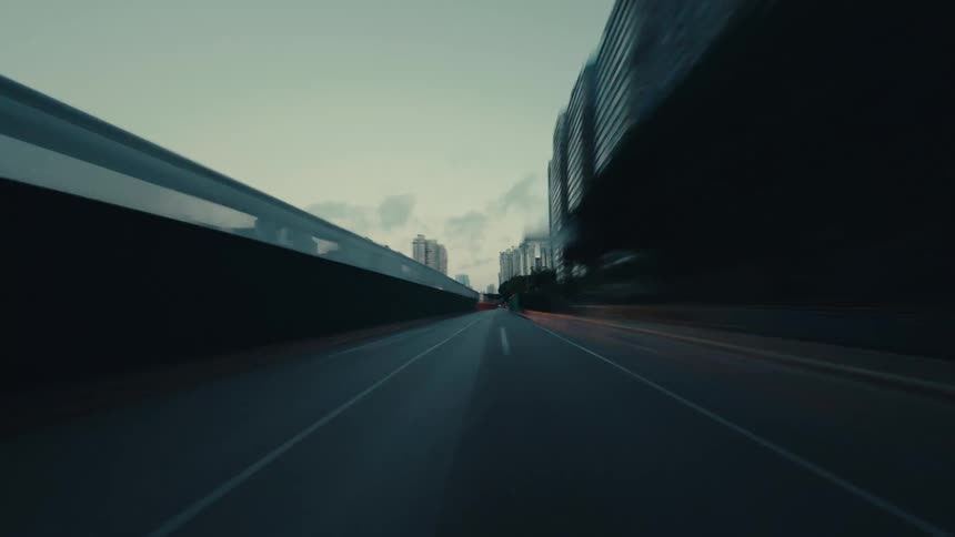 A moody, first-person hyperlapse drive through a modern city at dawn