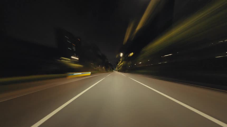 A thrilling first-person perspective hyperlapse captures a high-speed drive along an illuminated city highway at night