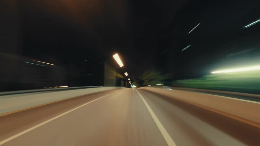 An immersive POV hyper-lapse captures the exhilarating speed of a nighttime drive through a city, with light trails streaking by
