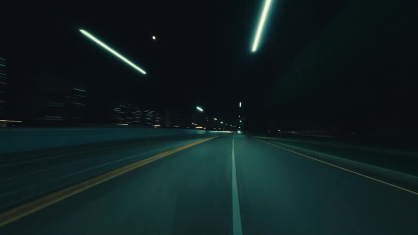 A dynamic POV hyper-lapse of driving down a city highway at night, with light trails creating a sense of speed