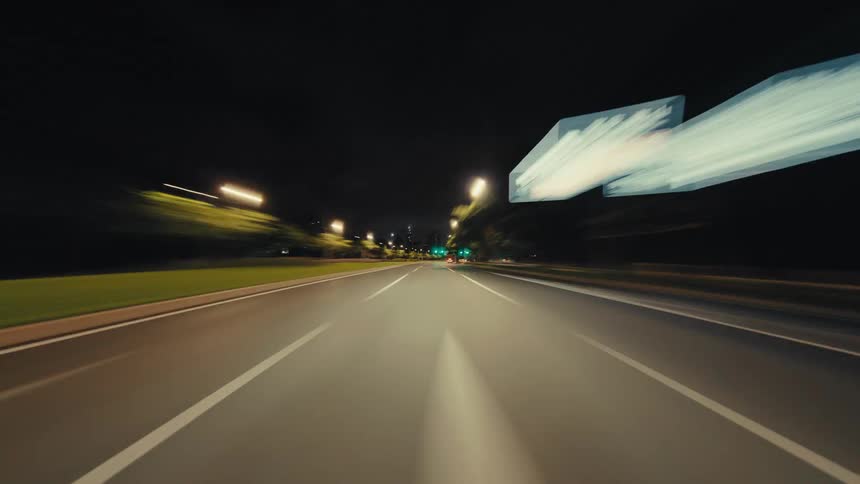 A dynamic point-of-view hyperlapse of a car speeding through illuminated city streets at night