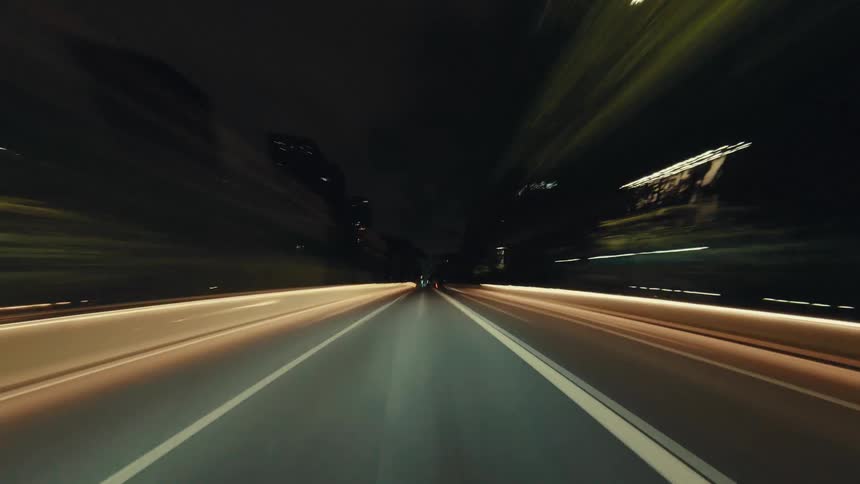 Experience the blur of city lights in this exhilarating POV hyperlapse of a car speeding down a highway at night