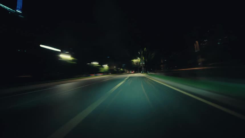 A driver's POV hyperlapse shows a high-speed journey through a modern city at night, with streetlights creating streaks of light