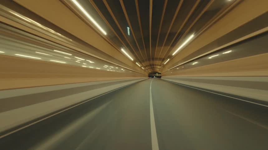 Point-of-view hyperlapse of a high-speed drive through an illuminated city tunnel and along a highway at night