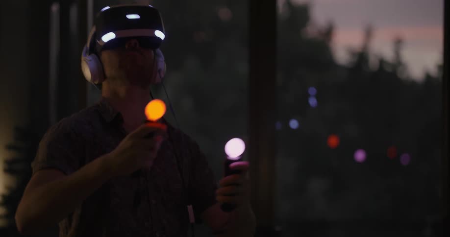 Man looking into a virtual reality machine and waving his arms around