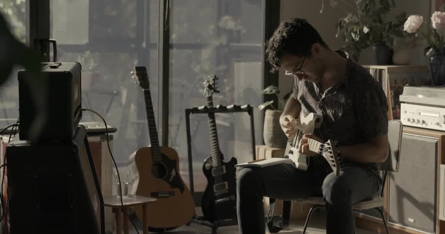 A man sits and strums a guitar