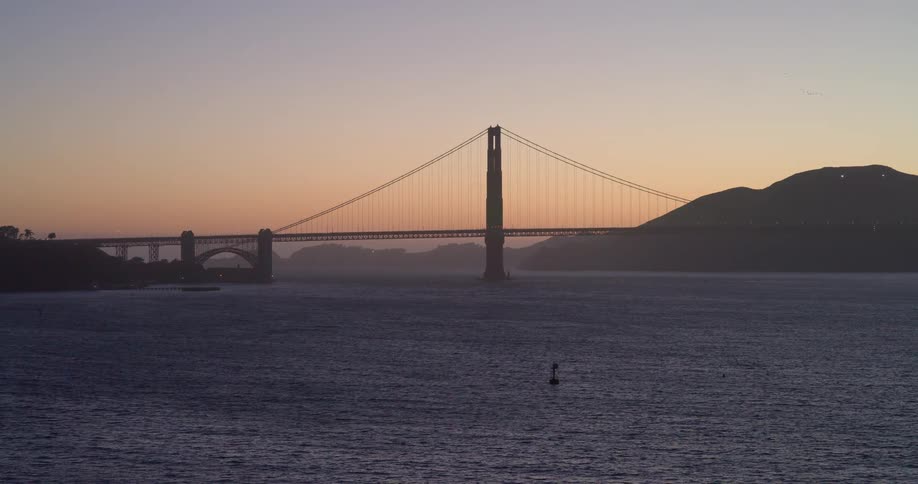 The Golden Gate Bridge is silhouetted against a beautiful twilight sky over the San Francisco Bay