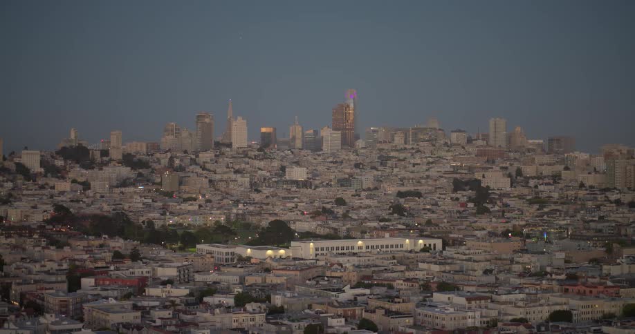 Slowly zooming in on the vast San Francisco cityscape as lights begin to dot the buildings during the twilight hour