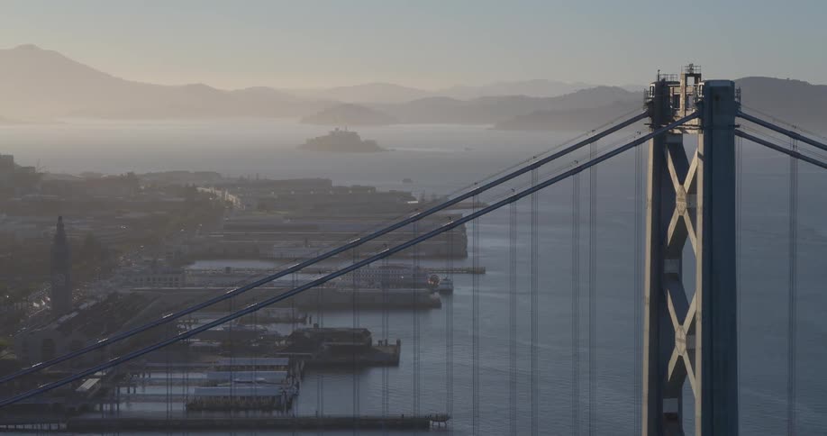 A slow zoom out reveals the San Francisco Bay Bridge at sunrise, with Alcatraz and the hazy city waterfront in the background