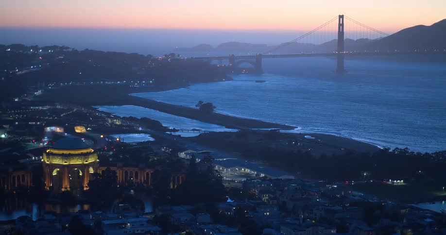 An iconic wide shot of the illuminated Palace of Fine Arts and Golden Gate Bridge in San Francisco at twilight