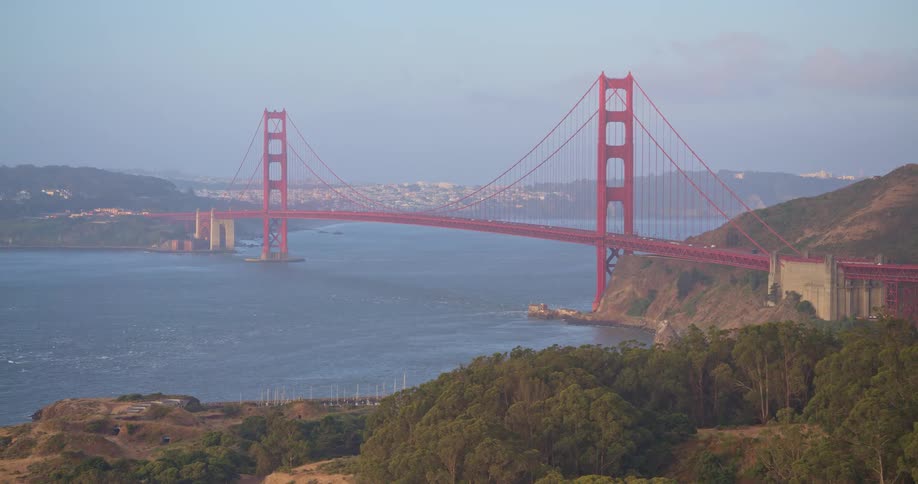 A slow aerial pullback reveals the iconic Golden Gate Bridge connecting San Francisco to the Marin Headlands on a hazy morning