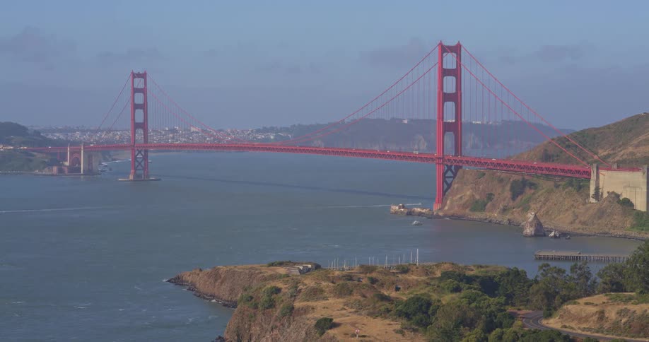 A slow zoom-out shot captures a scenic wide view of the iconic Golden Gate Bridge over the San Francisco Bay on a sunny day