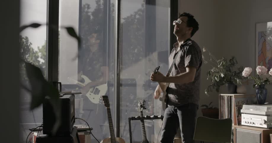 A man is playing guitar and bobbing his head