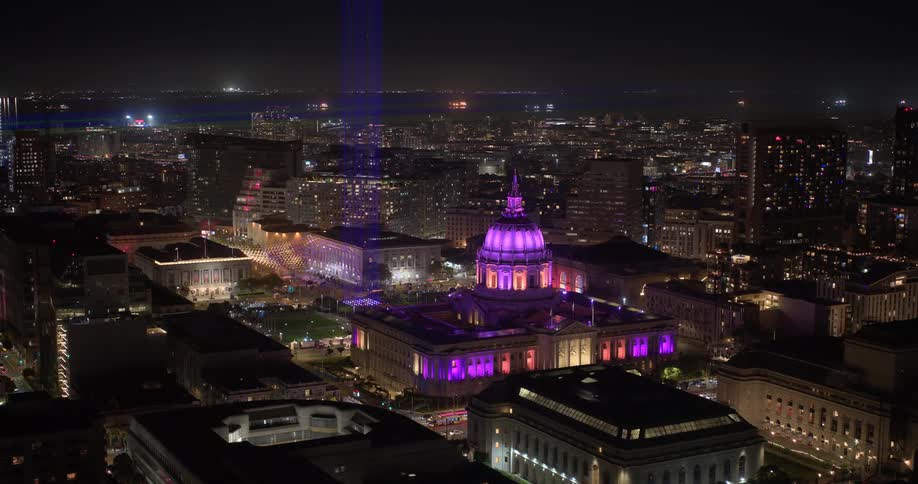 A stunning night time-lapse of San Francisco City Hall illuminated in vibrant purple lights, with a beam of light shooting into the sky