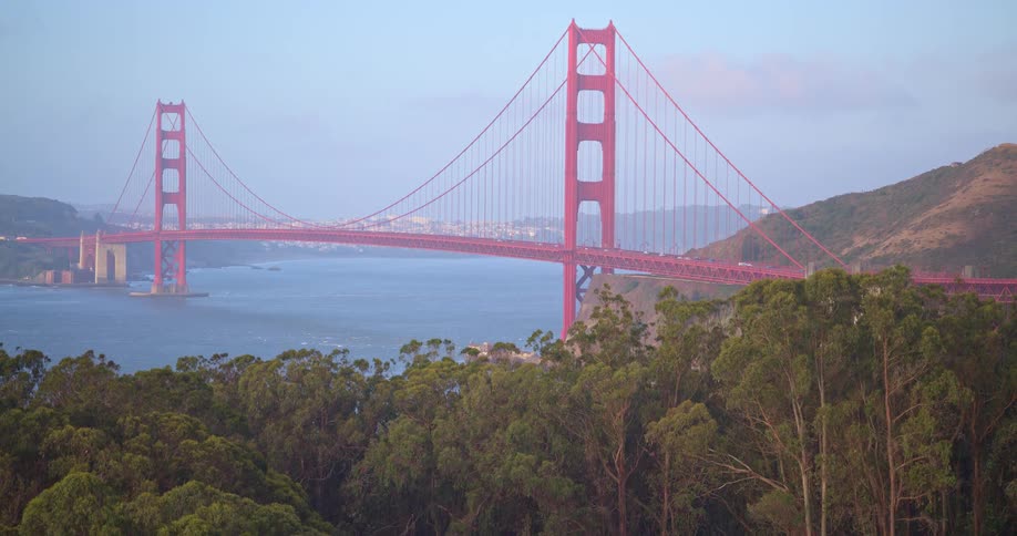 A scenic, slow zoom out shot reveals the lush Marin Headlands with the iconic Golden Gate Bridge and San Francisco bay in the background