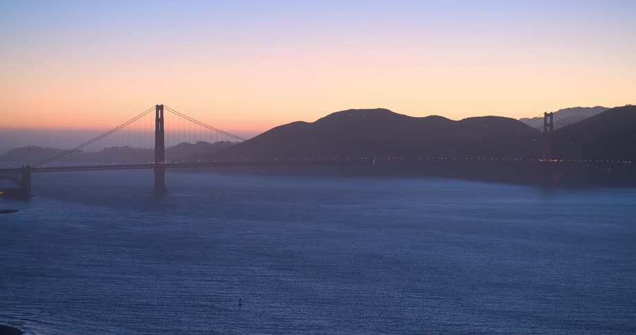 A scenic wide shot of the Golden Gate Bridge spanning the San Francisco Bay against a beautiful twilight sky