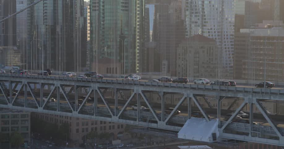 A slow pan reveals traffic moving across the iconic Bay Bridge with the hazy downtown San Francisco skyline visible in the background