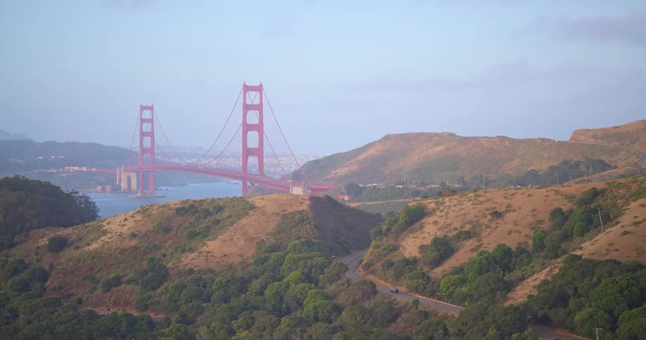 A slow zoom out from the Golden Gate Bridge reveals a winding road through the rolling hills of the Marin Headlands