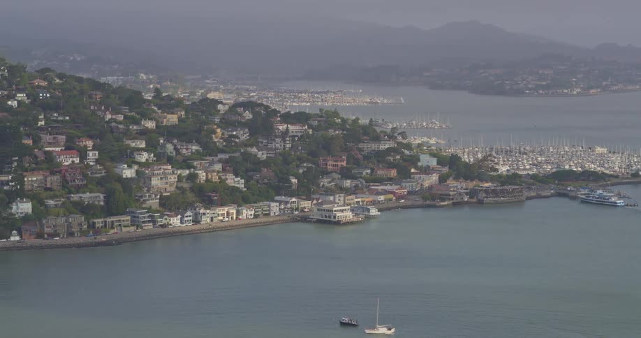 A hazy panoramic view showcases the beautiful seaside town of Sausalito, with its iconic hillside homes and bustling marina