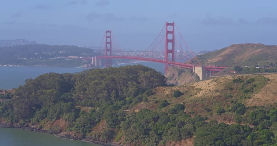 An aerial view pulls back from the iconic Golden Gate Bridge, revealing the lush Marin Headlands and the San Francisco Bay
