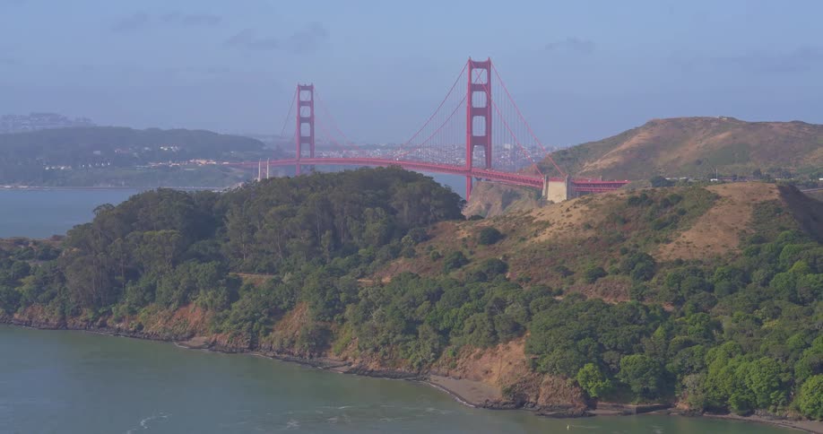 A majestic aerial view slowly pulls back to reveal the iconic Golden Gate Bridge and the verdant hills of the San Francisco Bay Area