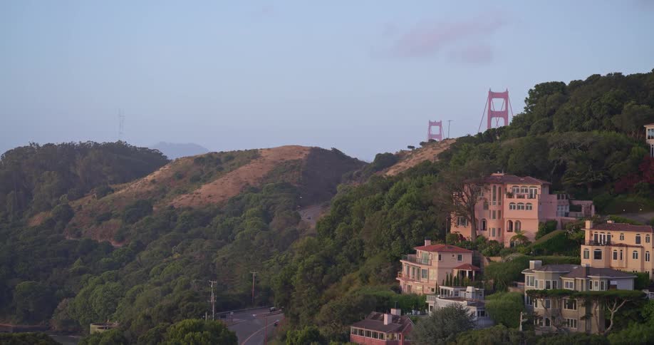 An aerial view rises over the waterfront homes of Sausalito, California, to reveal the iconic Golden Gate Bridge nestled in the Marin Headlands