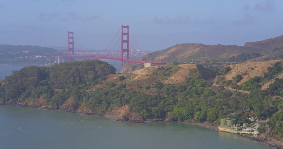 An aerial view pulls back to reveal the iconic Golden Gate Bridge and the hazy San Francisco Bay coastline