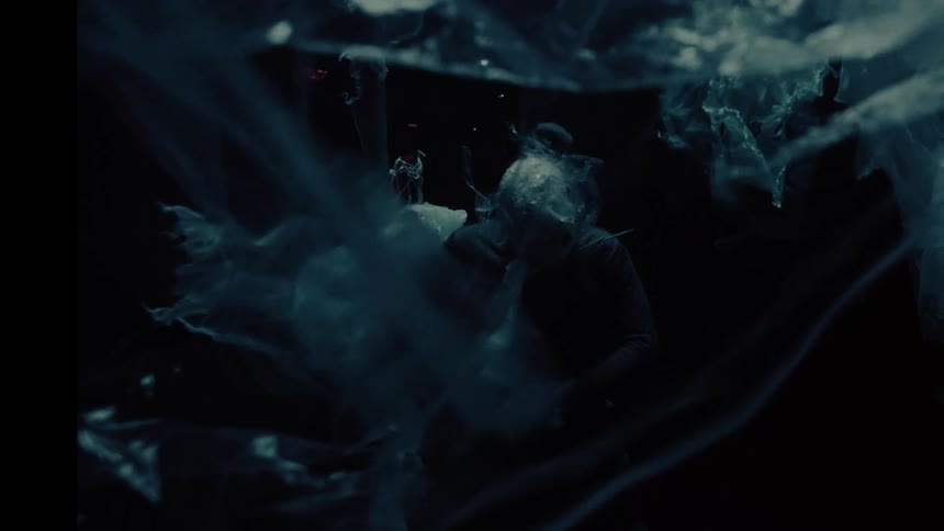 A conceptual and eerie shot of a person drowning and disappearing in a dark, plastic-polluted abyss