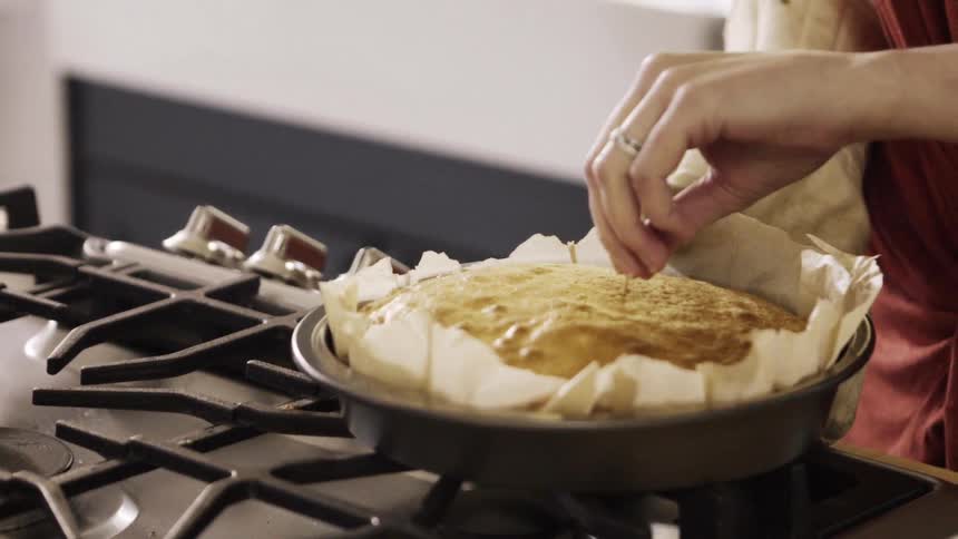 A woman puts a toothpick in a cake to test it
