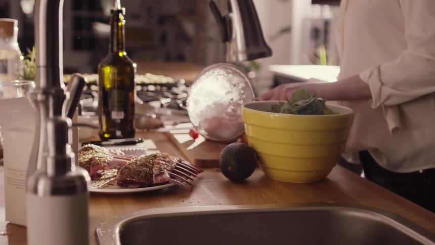 A woman pours washed tomatoes out of a colander onto a cutting board