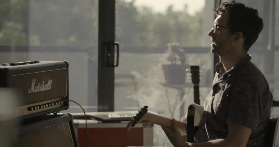 A man adjusts his amplifier to set his guitar
