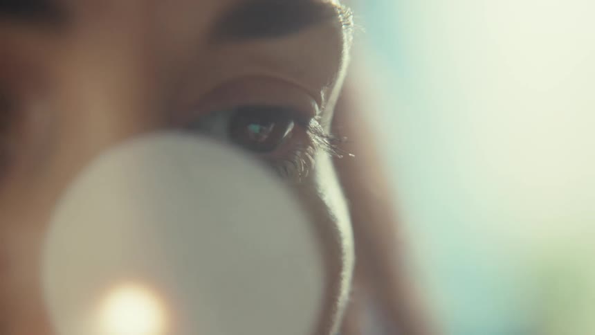 An artistic extreme close-up of a person's eye, with a slow focus pull revealing their eyelashes under soft, dreamy light