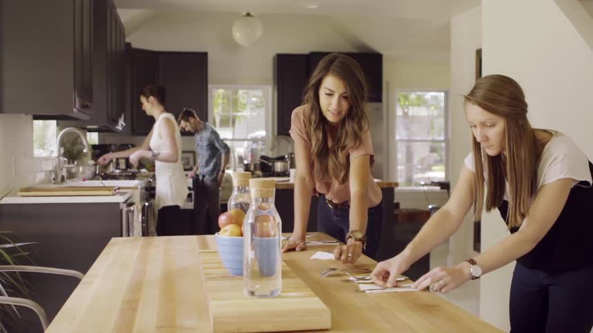 Two women setting a kitchen table during the day