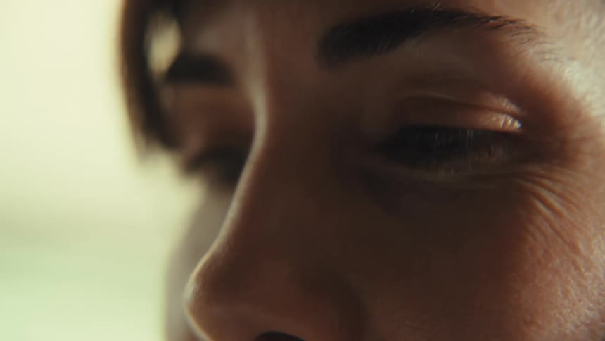 An extreme close-up shot slowly focuses on the eye of a woman in moody lighting