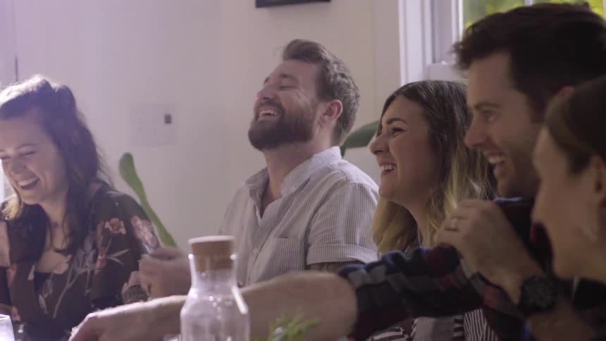 A group of people laugh while eating a meal