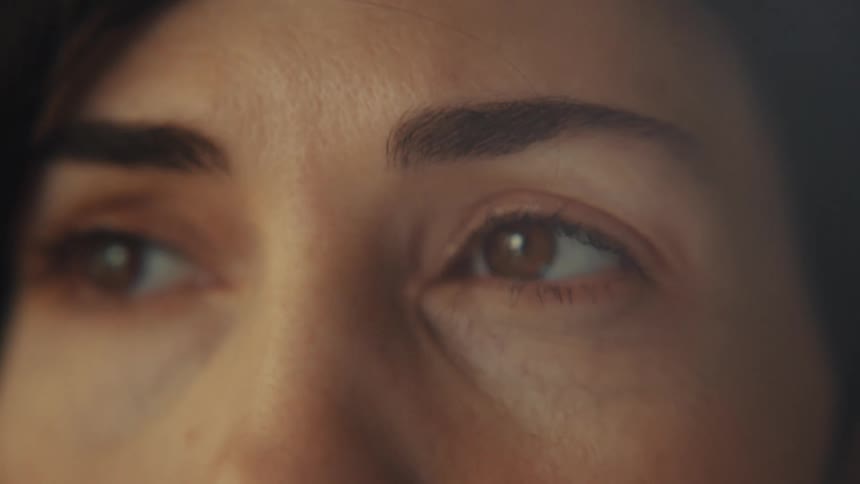 An intimate extreme close-up of a woman's face, slowly revealing her features from her eyes to her mouth