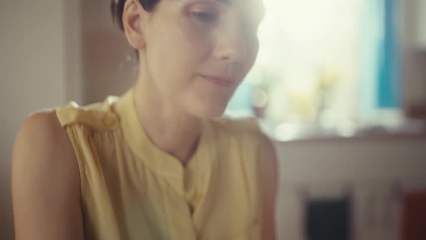 Close up of a focused woman in a sunlit room working at her desk while reviewing documents