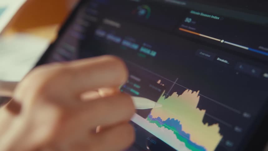Close-up of a cryptocurrency investor analyzing financial charts and data on a tablet with a stylus