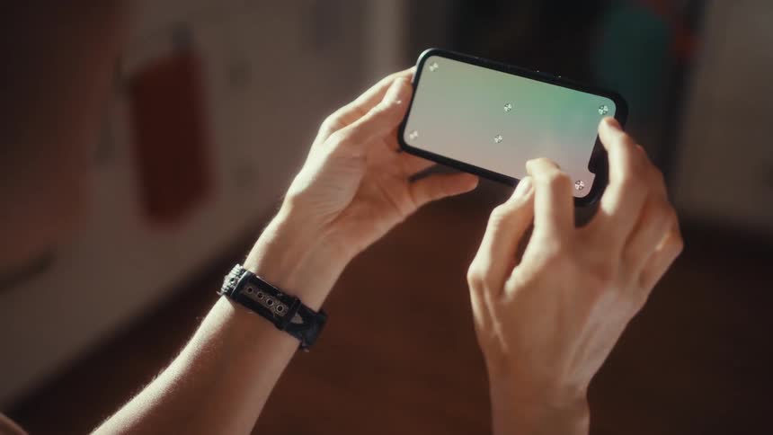 Close-up over the shoulder shot of a woman scrolling through content on a smartphone with a green screen