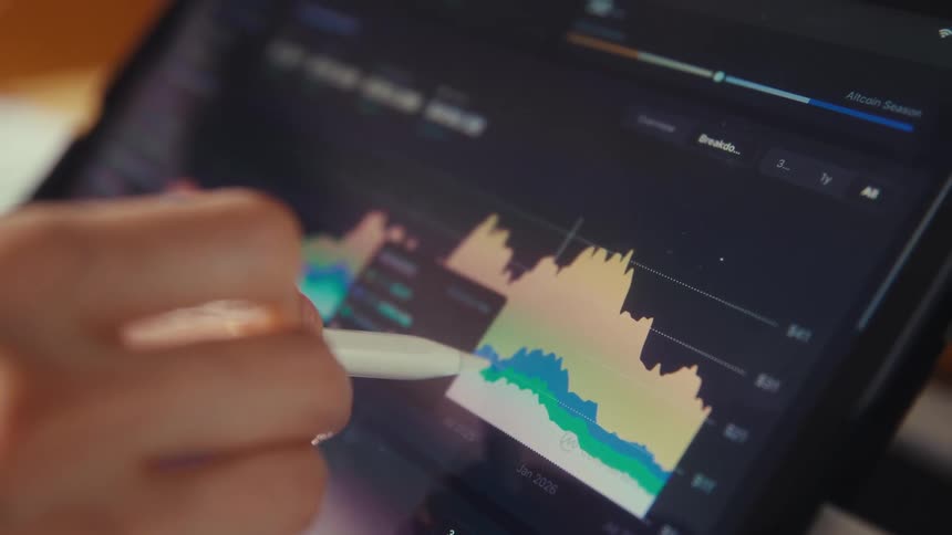 Close-up of a trader's hand using a stylus to analyze a cryptocurrency price chart on a tablet's screen
