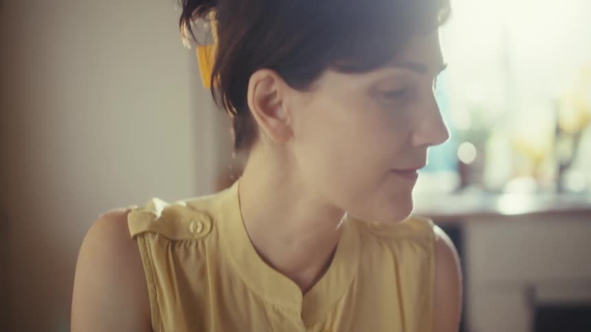 Slow-motion close-up of a woman working from home, reviewing papers and using a stylus on her tablet screen