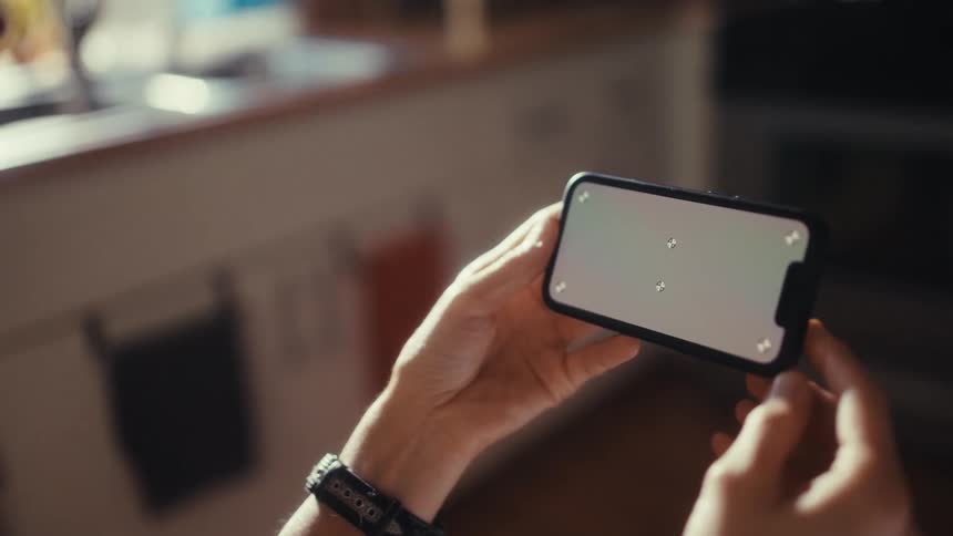 An over-the-shoulder shot of a person holding a smartphone horizontally with a screen ready for custom content