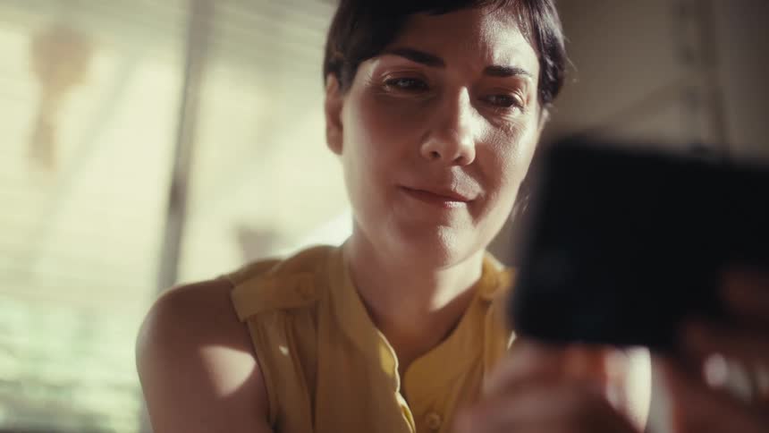 A slow push-in shot captures a woman's emotional journey from happiness to profound sadness as she reads something on her smartphone